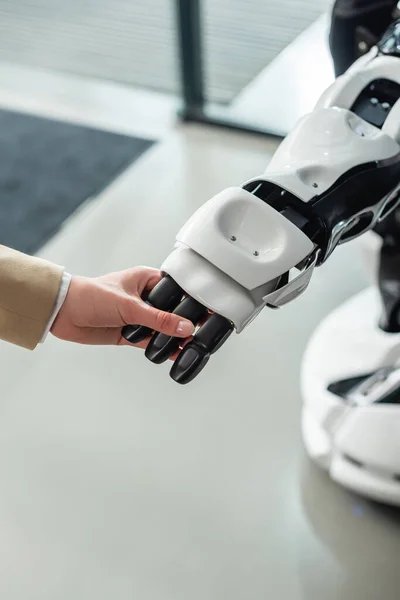 Частичный взгляд бизнесвумен, держащихся за руку гуманоидного робота — стоковое фото