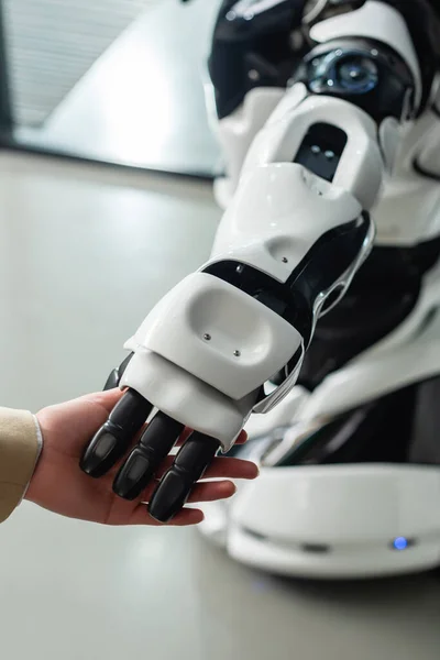 Visão cortada de empresária tocando mão de robô humanoide no escritório — Fotografia de Stock