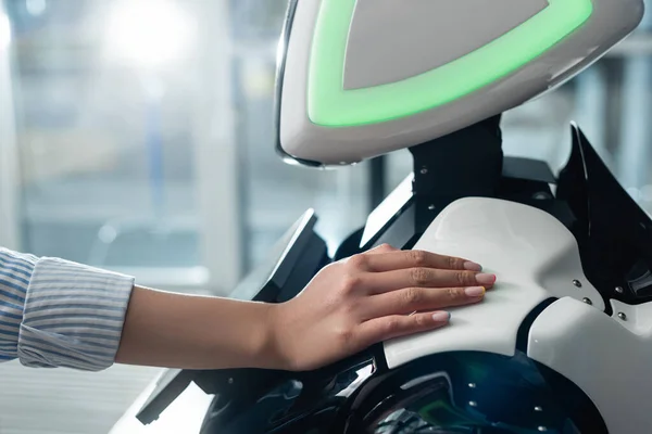 Vista recortada de mano femenina tocar robot en la oficina - foto de stock