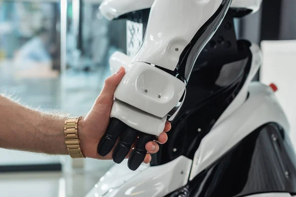 Visão parcial do empresário segurando a mão do robô — Fotografia de Stock