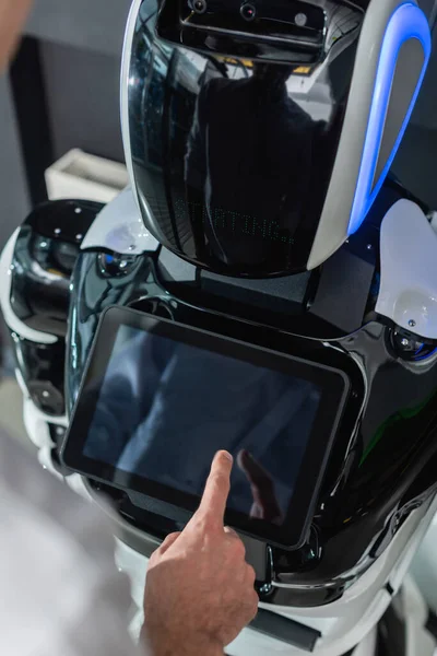 Cropped view of young engineer operating robot in office, blurred foreground — Stock Photo