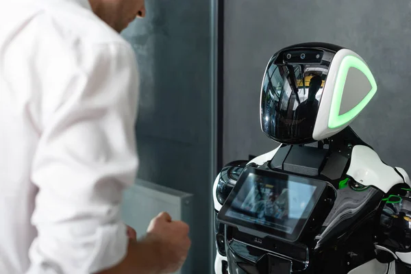 Cropped view of blurred engineer standing near humanoid robot in office — Stock Photo