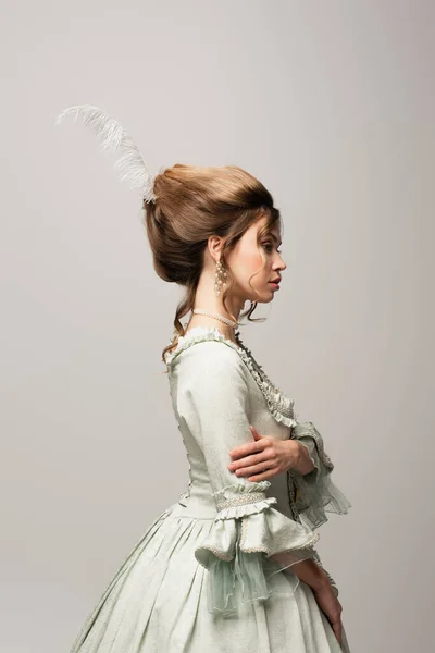 Vista lateral da mulher elegante em roupa retro posando isolado no cinza — Fotografia de Stock