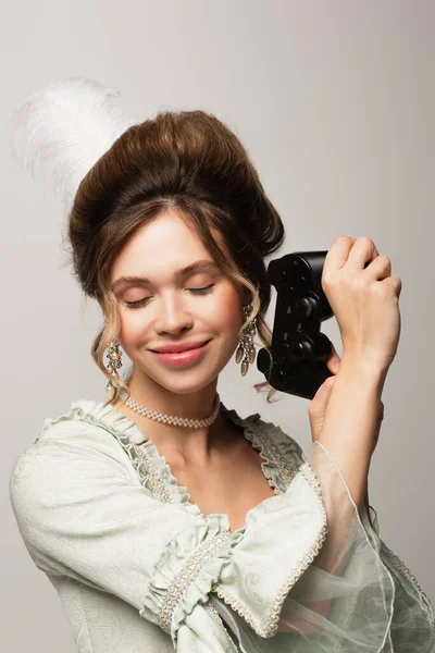 KYIV, UKRAINE - APRIL 22, 2021: pleased woman in vintage outfit holding gamepad isolated on grey — Stock Photo