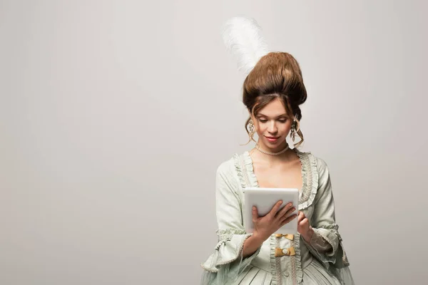 Красивая женщина в винтажном платье с помощью цифровой таблетки изолированы на серый — стоковое фото