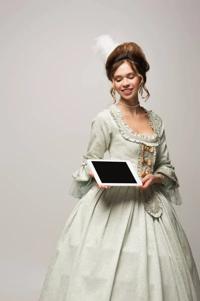 Femme heureuse en robe rétro tenant tablette numérique avec écran blanc isolé sur gris — Photo de stock