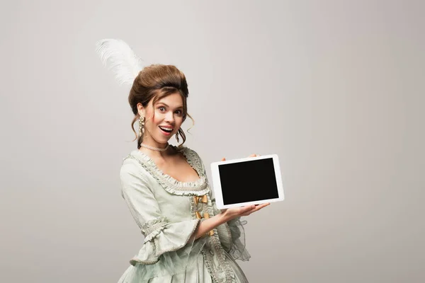 Mujer de estilo vintage asombrada mostrando tableta digital con pantalla en blanco aislada en gris - foto de stock