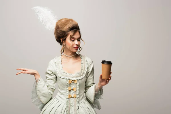 Young woman in stylish vintage clothing holding takeaway drink isolated on grey — Stock Photo