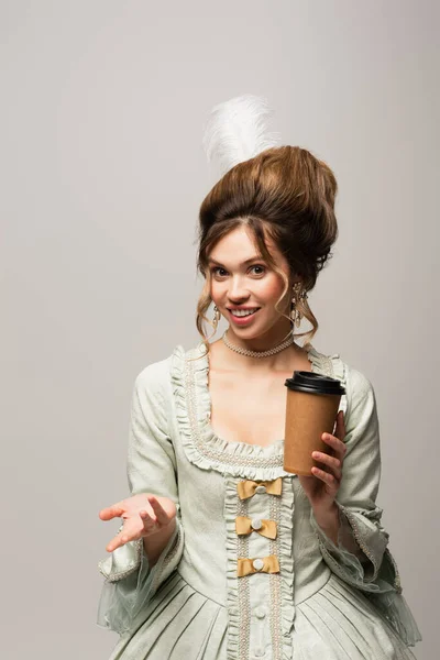 Smiling retro style woman with takeaway drink looking at camera isolated on grey — Stock Photo