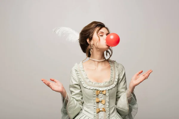 Élégante femme en tenue vintage soufflant gomme à bulles rouge isolé sur gris — Photo de stock