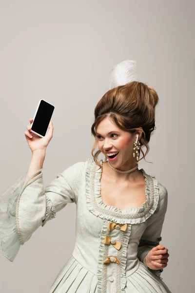 Excited retro style woman holding mobile phone with blank screen isolated on grey — Stock Photo