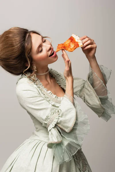 Giovane donna in elegante abito vintage mangiare pizza ad occhi chiusi isolato su grigio — Foto stock