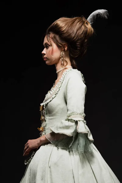 Side view of woman in elegant retro dress posing isolated on black — Stock Photo