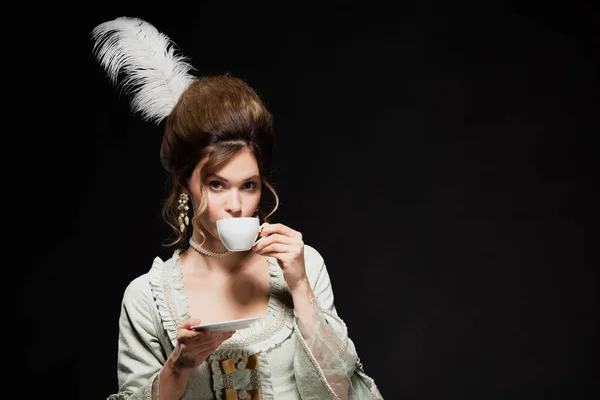 Mulher elegante em roupa retro beber café isolado em preto — Fotografia de Stock