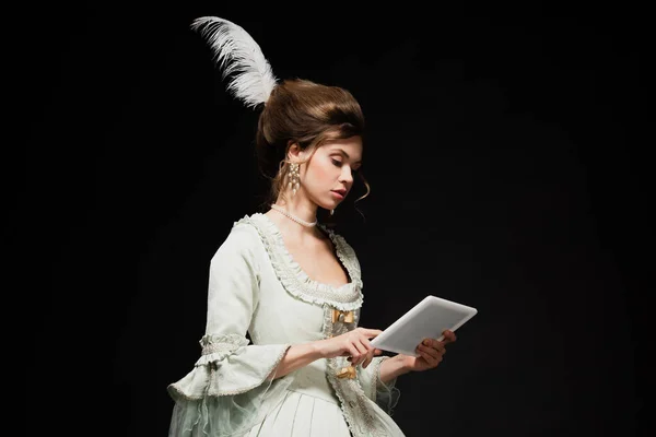 Young woman in elegant vintage dress using digital tablet isolated on black — Stock Photo