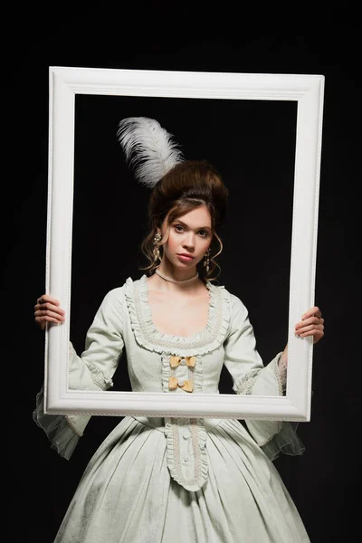 Charming woman in elegant vintage outfit holding white framing isolated on black — Stock Photo