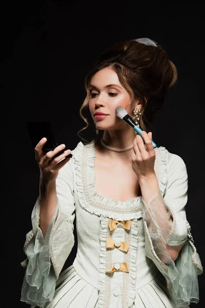 Pretty woman in elegant vintage outfit applying face powder isolated on black — Stock Photo