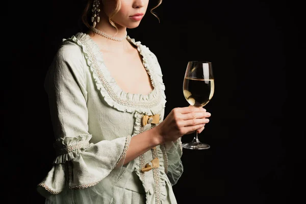 Partial view of young woman in retro dress holding glass of white wine isolated on black — Stock Photo