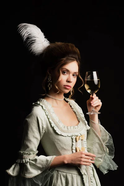 Pretty woman in vintage pastel grey dress holding glass of white wine isolated on black — Stock Photo