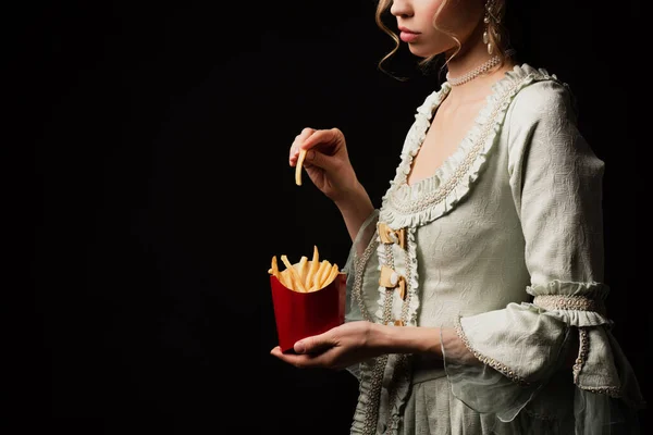 Cropped view of elegant woman in vintage dress holding french fries isolated on black — Stock Photo