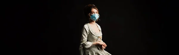 Элегантная женщина в винтажном пастельно-сером платье и защитная маска изолированы на черном, баннер — стоковое фото
