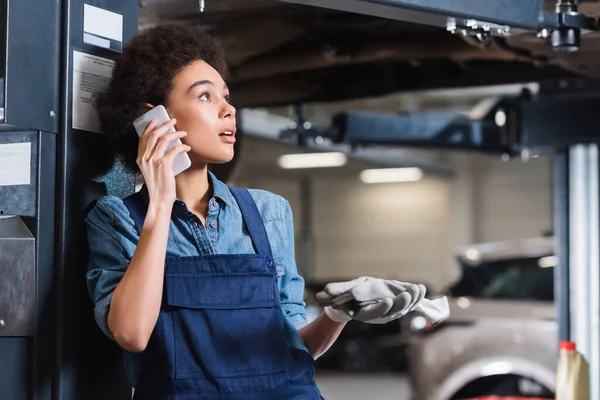 Besorgter junger afrikanisch-amerikanischer Mechaniker telefoniert in Garage — Stockfoto