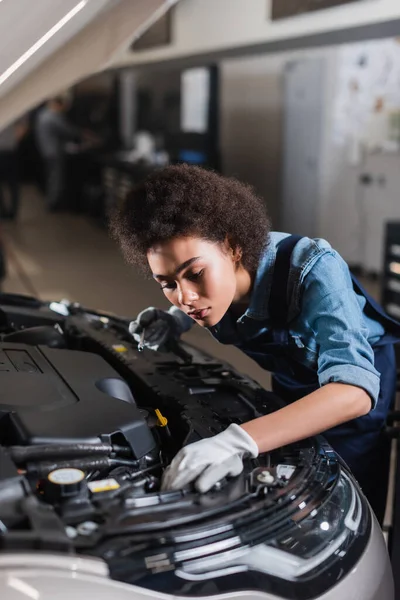 Giovane meccanico afroamericano con chiave inglese e motore di fissaggio auto in garage — Foto stock