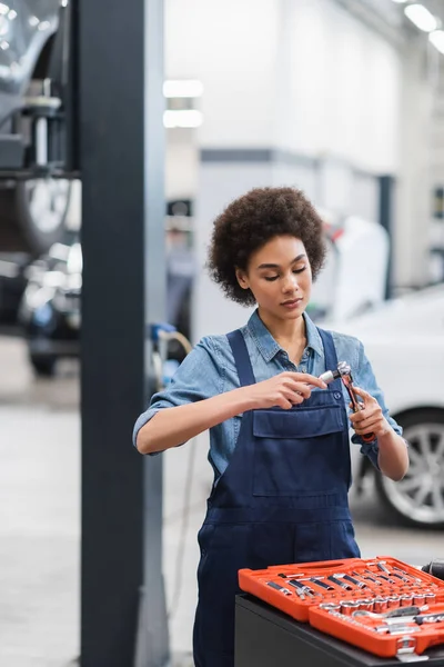 Young african american mechanic holding equipment in auto repair garage — Stock Photo
