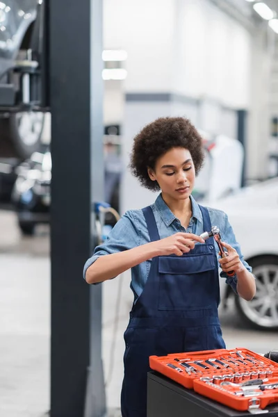 Giovane africano americano meccanico attrezzature di tenuta in garage di riparazione auto — Foto stock