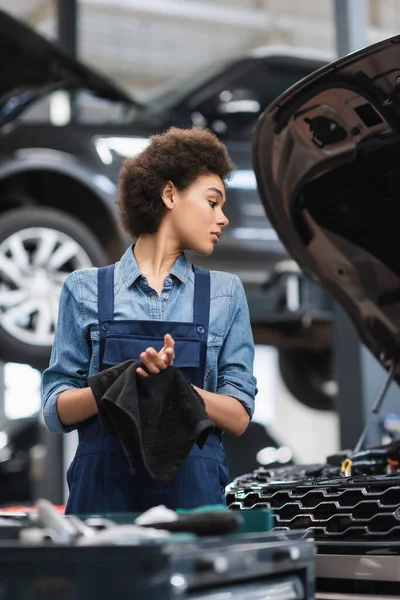 Junge afrikanisch-amerikanische Mechaniker in Overalls trocknen Hände mit Handtuch in der Garage — Stockfoto