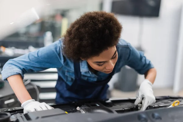 Joven afroamericano mecánico de fijación de motor de coche en el garaje - foto de stock