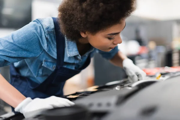 Young african american mechanic repairing car motor in garage — Stock Photo