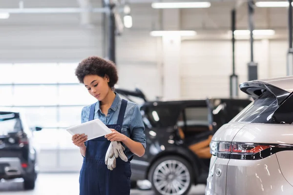 Junger afrikanisch-amerikanischer Mechaniker schaut in Garage auf digitales Tablet — Stockfoto