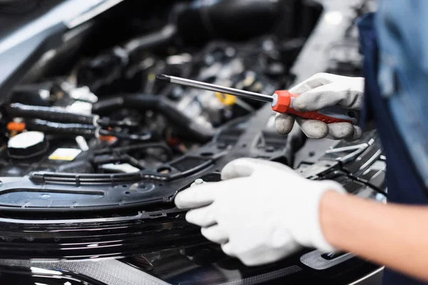 Close up view of female mechanic hands in gloves repairing car motor with screwdriver in garage — Stock Photo