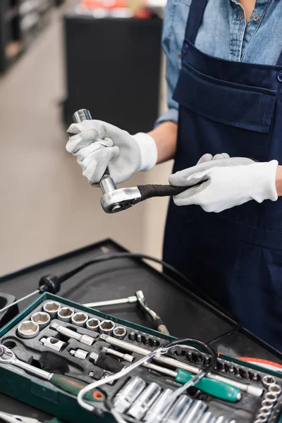 Vista de cerca de manos mecánicas en guantes que sostienen la llave inglesa en el garaje - foto de stock