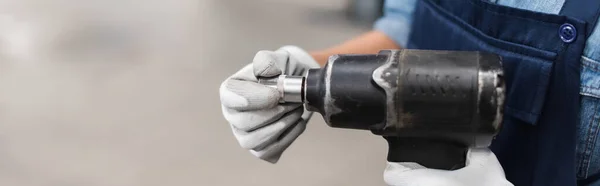 Nahaufnahme der Hände des Mechanikers in Handschuhen mit elektrischem Schraubenzieher und Befestigung auf verschwommenem Hintergrund, Banner — Stockfoto