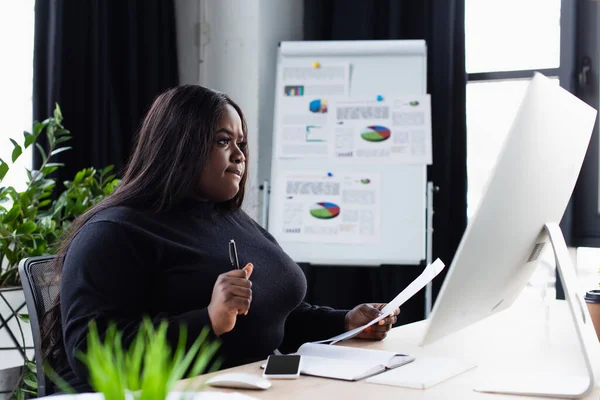 Afrikanisch-amerikanische Plus-Size-Unternehmerin schaut im Büro auf Computermonitor — Stockfoto