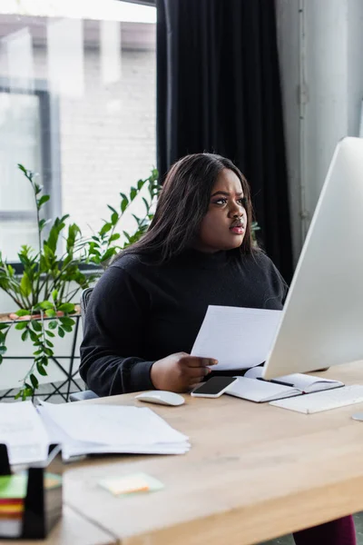 Konzentrierte afrikanisch-amerikanische Plus-Size-Unternehmerin blickt im Büro auf Computermonitor — Stockfoto