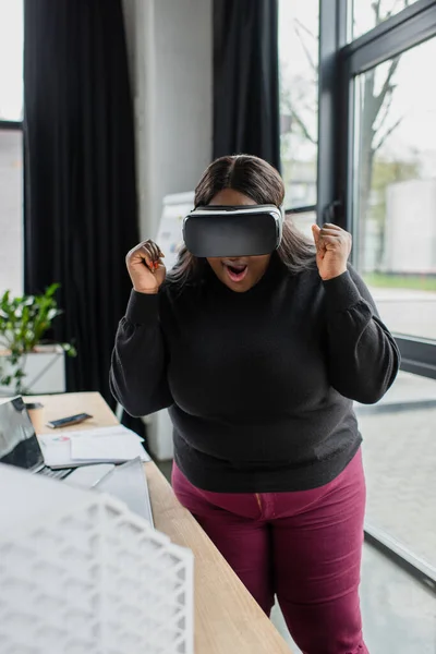 Sorpreso africano americano plus size ingegnere in auricolare vr vicino modello di casa sfocata — Foto stock