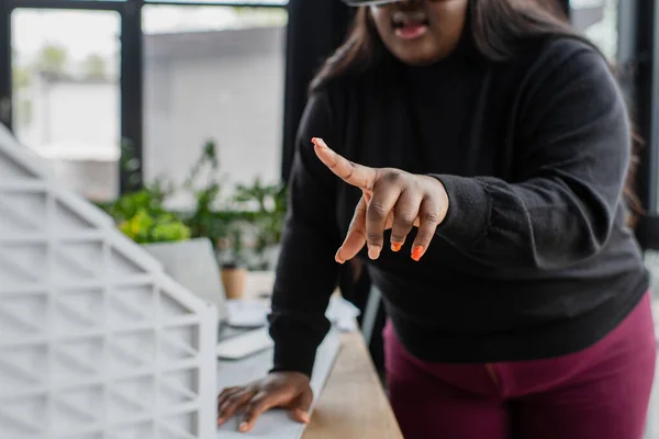 Abgeschnittene Ansicht einer verschwommenen afrikanisch-amerikanischen Plus-Size-Frau, die auf verschwommenes Papphausmodell zeigt — Stockfoto