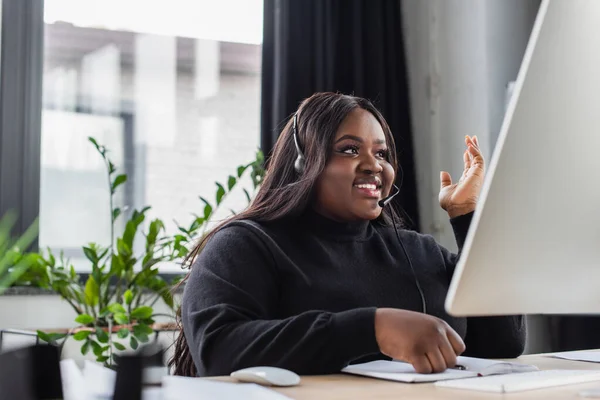 Sorridente afro-americano plus size operador em fone de ouvido com microfone no escritório — Fotografia de Stock