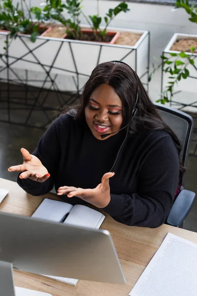 Vue grand angle de heureux opérateur afro-américain plus la taille dans le casque avec geste de microphone dans le bureau — Photo de stock