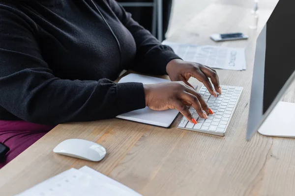 Частичный взгляд африканской американской предпринимательницы, печатающей на компьютерной клавиатуре в офисе — стоковое фото