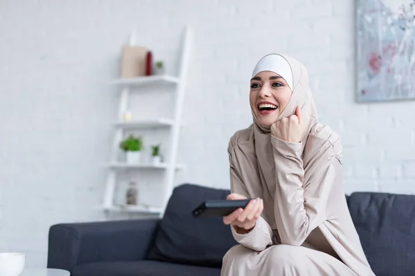 Aufgeregte arabische Frau lacht, während sie sich zu Hause einen Film ansieht — Stockfoto