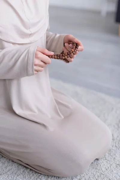 Abgeschnittene Ansicht einer muslimischen Frau, die zu Hause auf Knien betet — Stockfoto