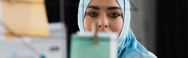 Femme d'affaires musulmane regardant des notes en papier sur le premier plan flou, bannière — Photo de stock