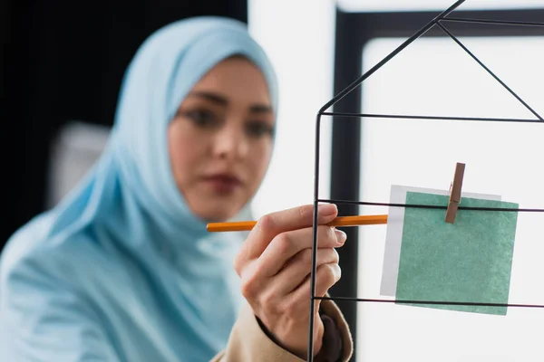 Mujer de negocios musulmana borrosa apuntando con lápiz a la nota de papel - foto de stock