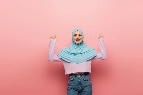 Animado muçulmano mulher no hijab e jeans mostrando alegria gesto no fundo rosa — Fotografia de Stock