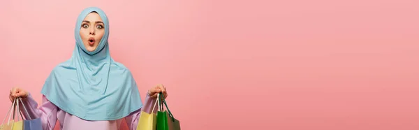 Mulher árabe emocionado no hijab segurando compras isoladas em rosa, banner — Fotografia de Stock