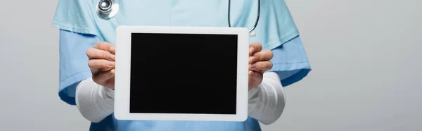 Обрезанный вид мусульманского врача, показывающий цифровую табличку с чистым экраном, изолированным на сером, баннер — стоковое фото